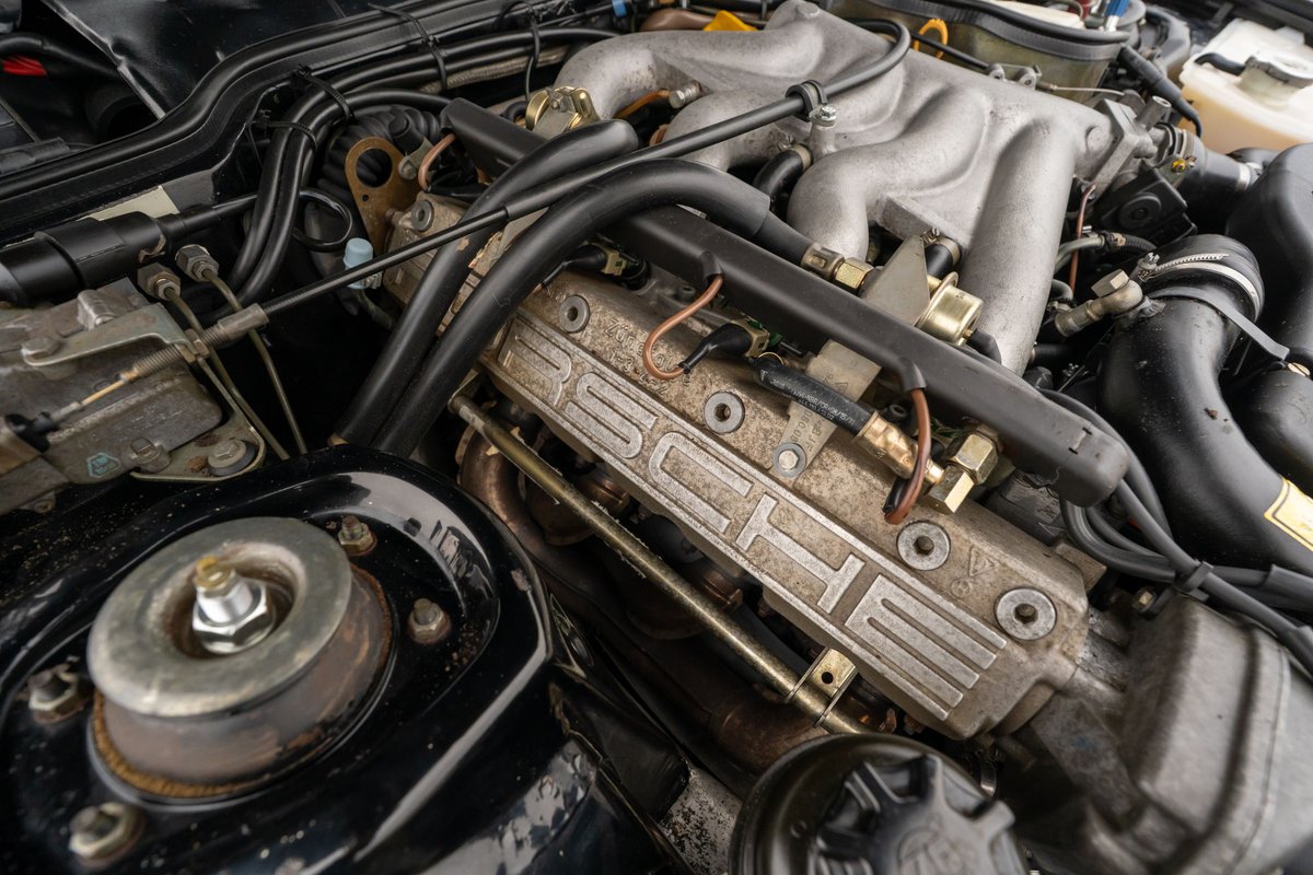 Closeup of a 1986 Porsche 944 Turbo engine bay, showing the PORSCHE embossed valve cover.