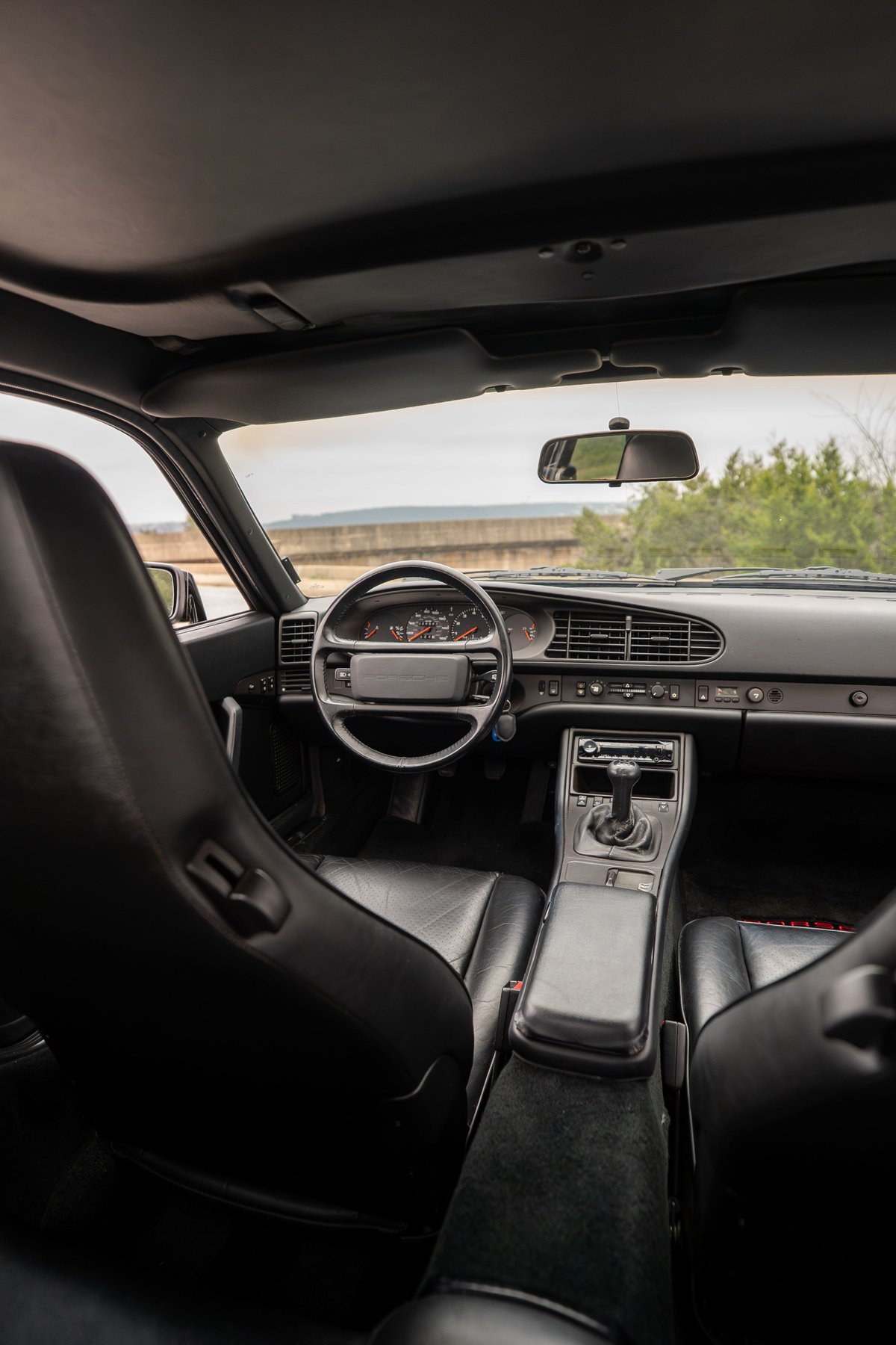 Interior view of a black 1986 Porsche 944 Turbo, showing leather seats and dashboard.