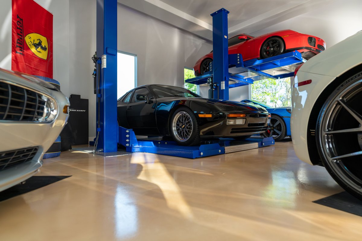 Black 1986 Porsche 944 Turbo on a lift, with multi-level parking and other cars.