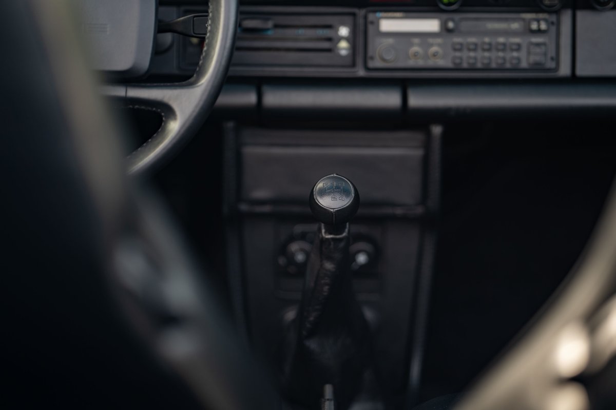 Close-up of a black manual shifter in a 1988 Porsche 930 Turbo Slantnose interior.
