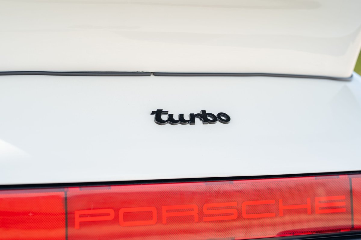 Close-up of a white 1988 Porsche 930 Turbo slantnose rear badge.