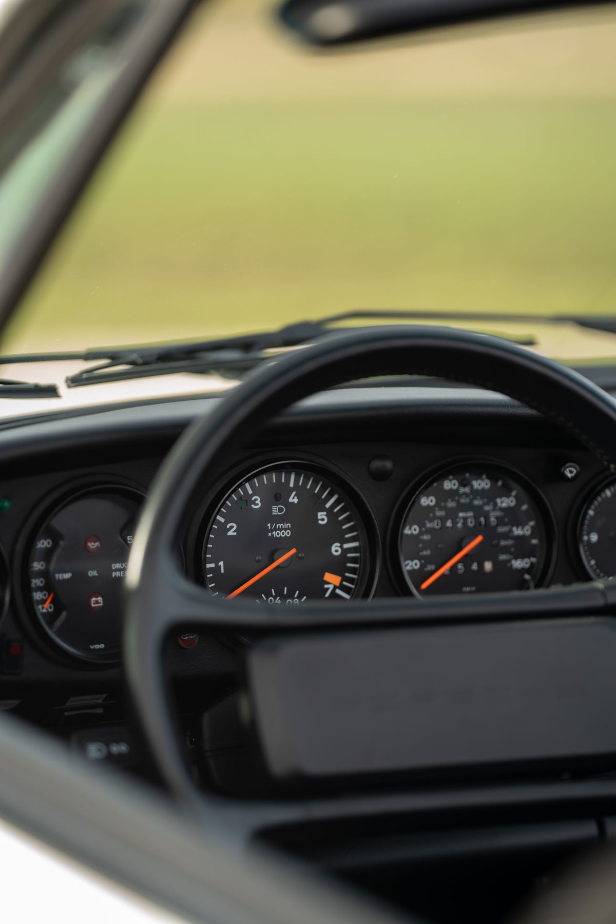 Interior of a white 1988 Porsche 930 Turbo Slantnose, showing the instrument cluster with tachometer.