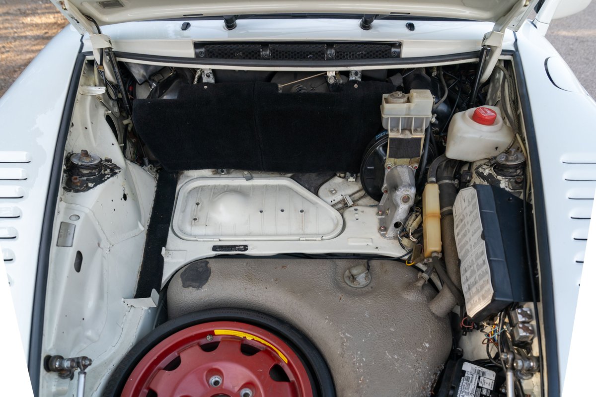 White 1988 Porsche 930 Slantnose front trunk with spare tire and engine components.
