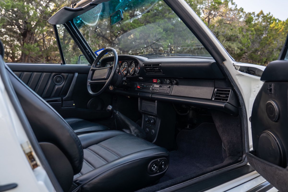 Interior view of a white 1988 Porsche 930 Turbo Slantnose convertible with black leather seats.