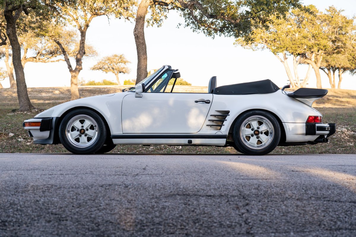 White 1988 Porsche 930 Slantnose convertible with a whale tail spoiler and Fuchs rims.