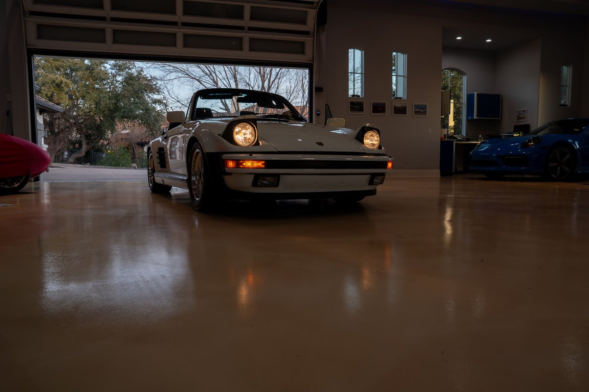 White 1988 Porsche 930 Turbo Slantnose convertible with pop-up headlights, Fuchs rims, and black trim.