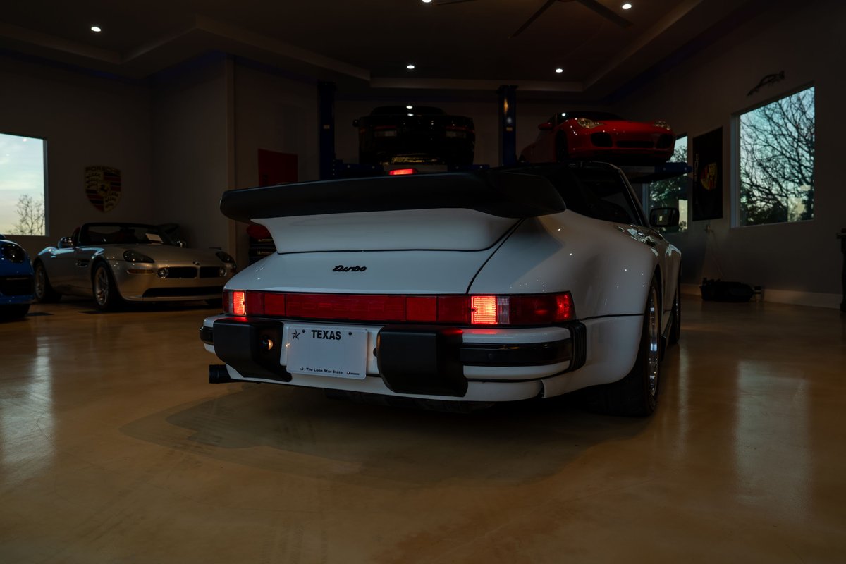 White 1988 Porsche 930 Turbo Slantnose with a prominent whale tail spoiler and wide rear fenders.