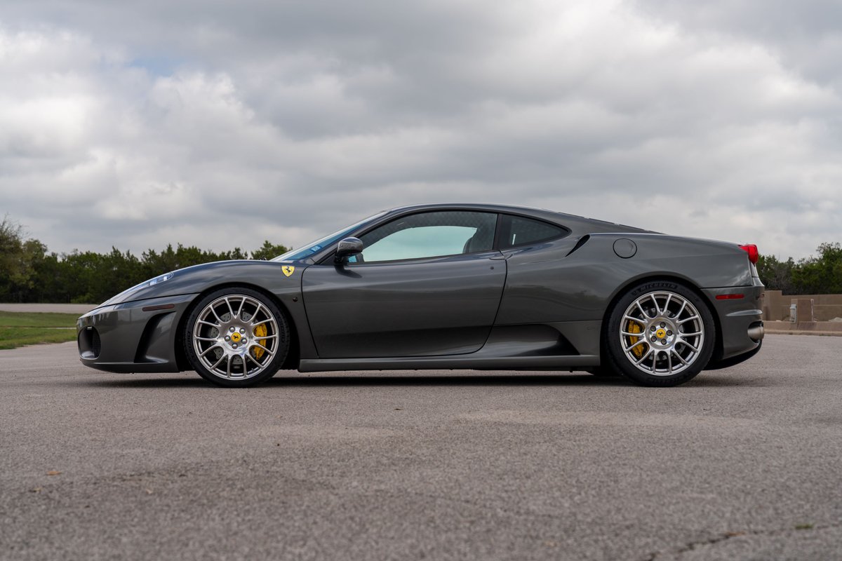 Side profile of a Grigio Silverstone 2007 Ferrari F430 with silver multi-spoke rims and yellow brake calipers.