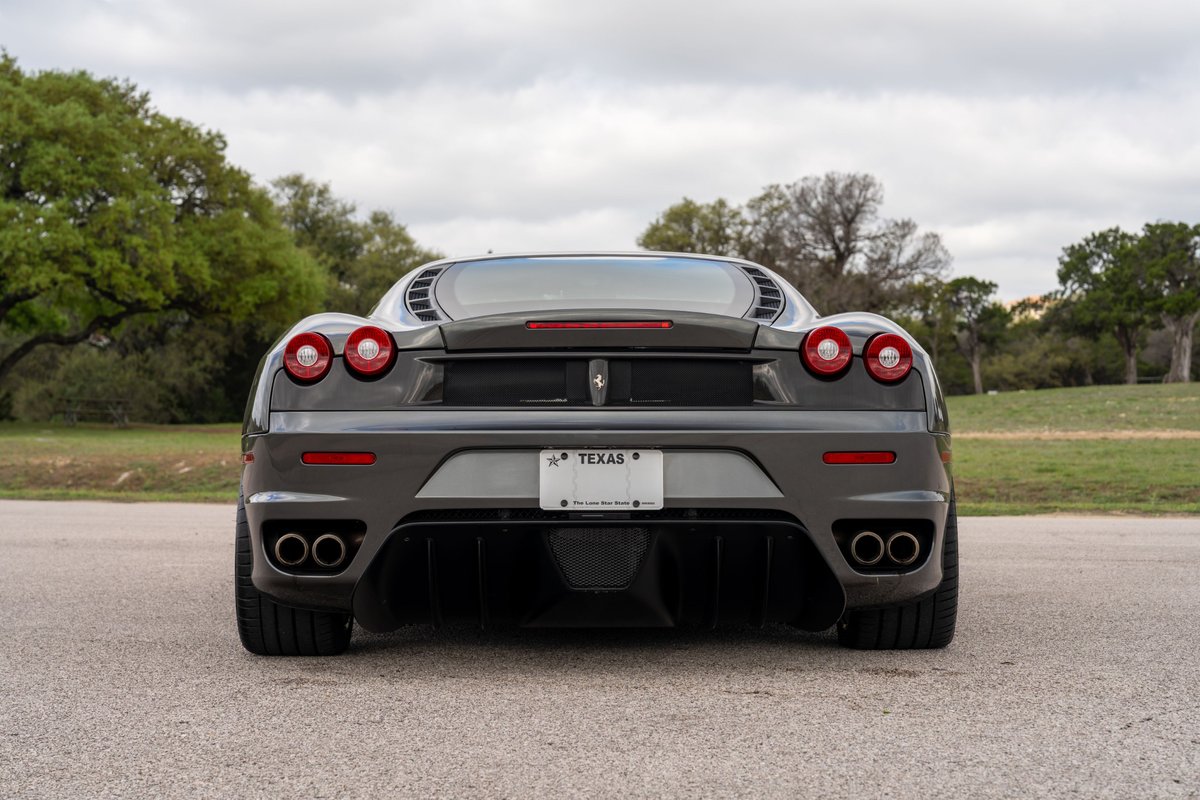 Rear view of a Grigio Silverstone 2007 Ferrari F430 6-speed with quad exhaust tips.