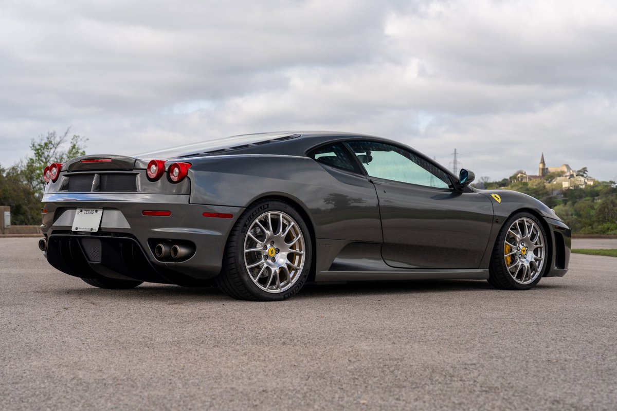 2007 Ferrari F430 6-speed in Grigio Silverstone. Rear three-quarter view shows silver rims and yellow brake calipers.
