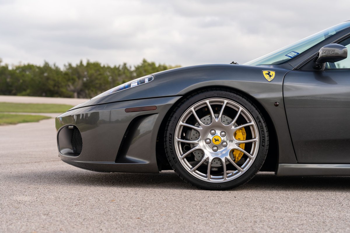 2007 Ferrari F430 in Grigio Silverstone, showing its front fender and multi-spoke alloy rims with yellow brake calipers.