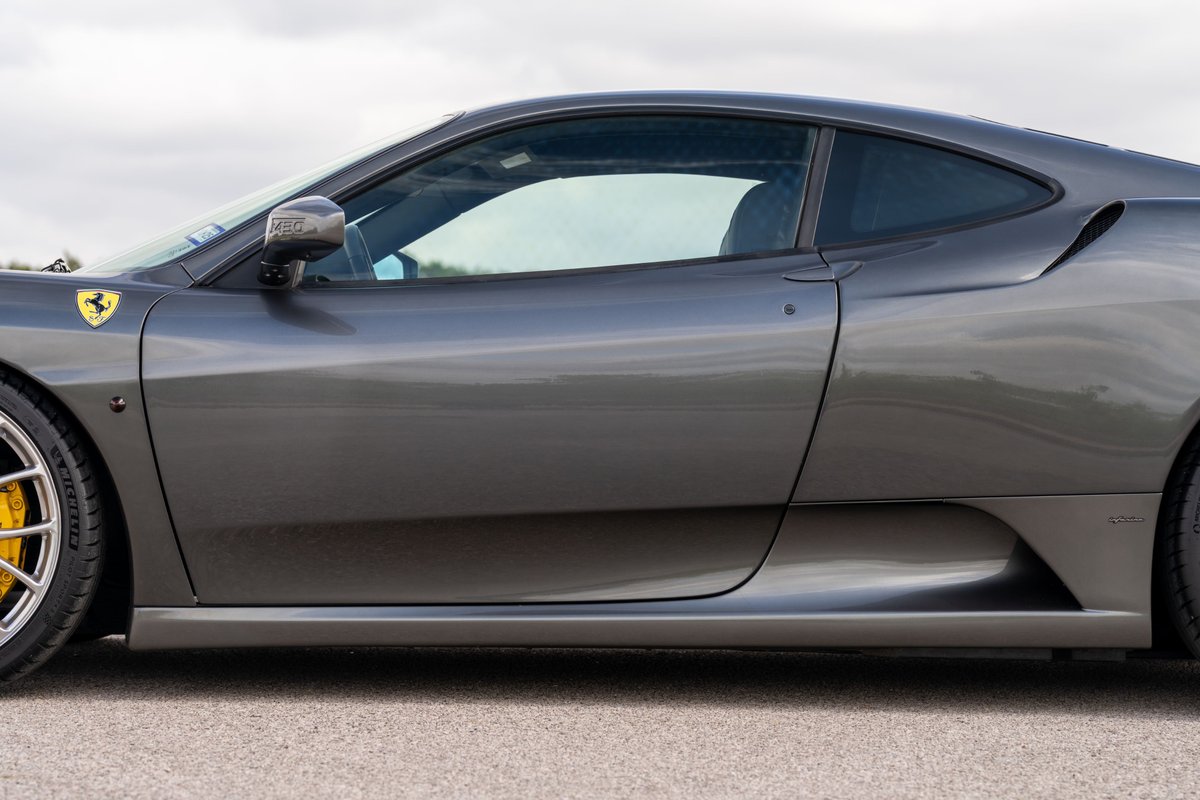 Close-up of a Grigio Silverstone 2007 Ferrari F430's side profile, showing yellow brake calipers behind silver rims.