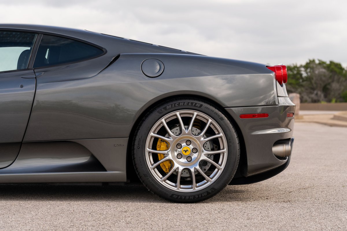 Close-up of a Grigio Silverstone 2007 Ferrari F430's rear wheel and side trim.