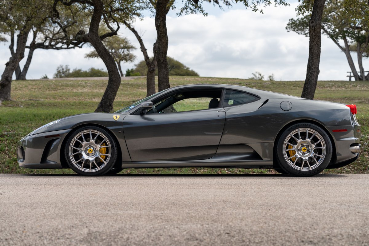 A Grigio Silverstone 2007 Ferrari F430 6-speed with aftermarket silver rims and yellow brake calipers.