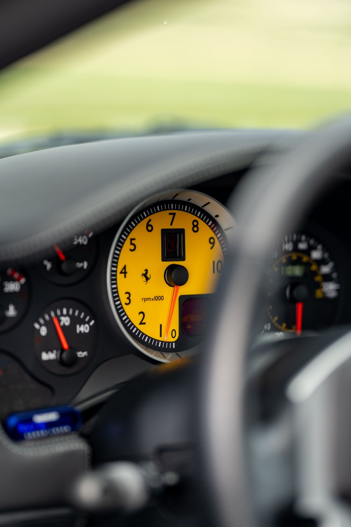 Close-up of yellow tachometer in a Grigio Silverstone 2007 Ferrari F430, showing RPM.