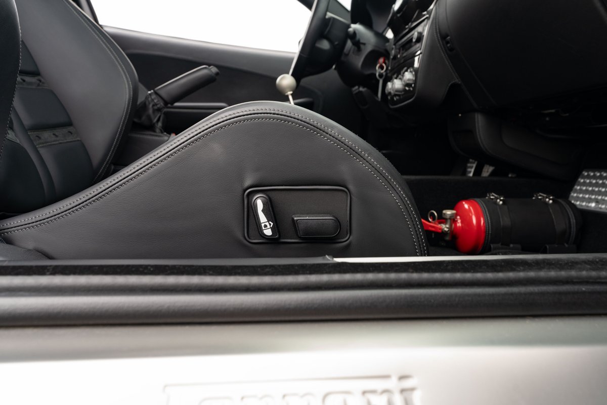 Ferrari F430 6-speed interior showing racing seat controls and fire extinguisher.