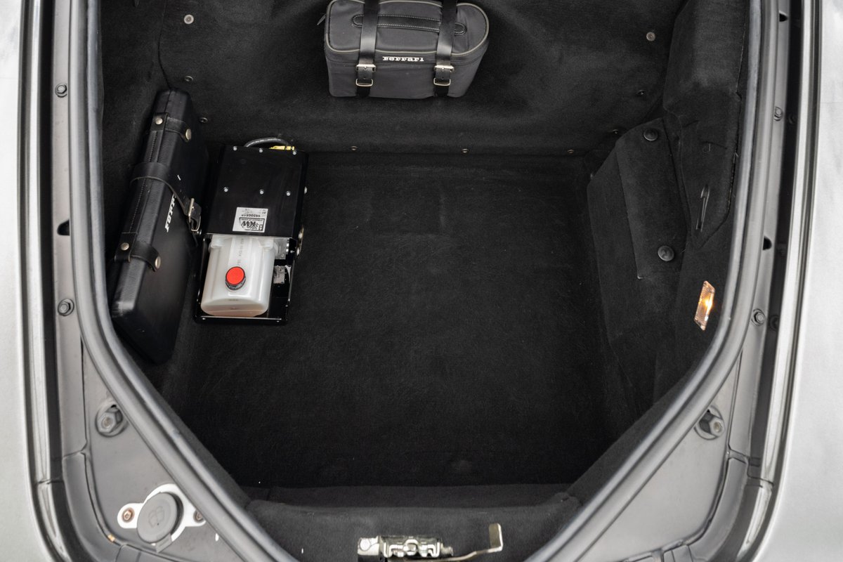 Trunk of a 2007 Ferrari F430 in Grigio Silverstone with hydraulic pump and luggage.