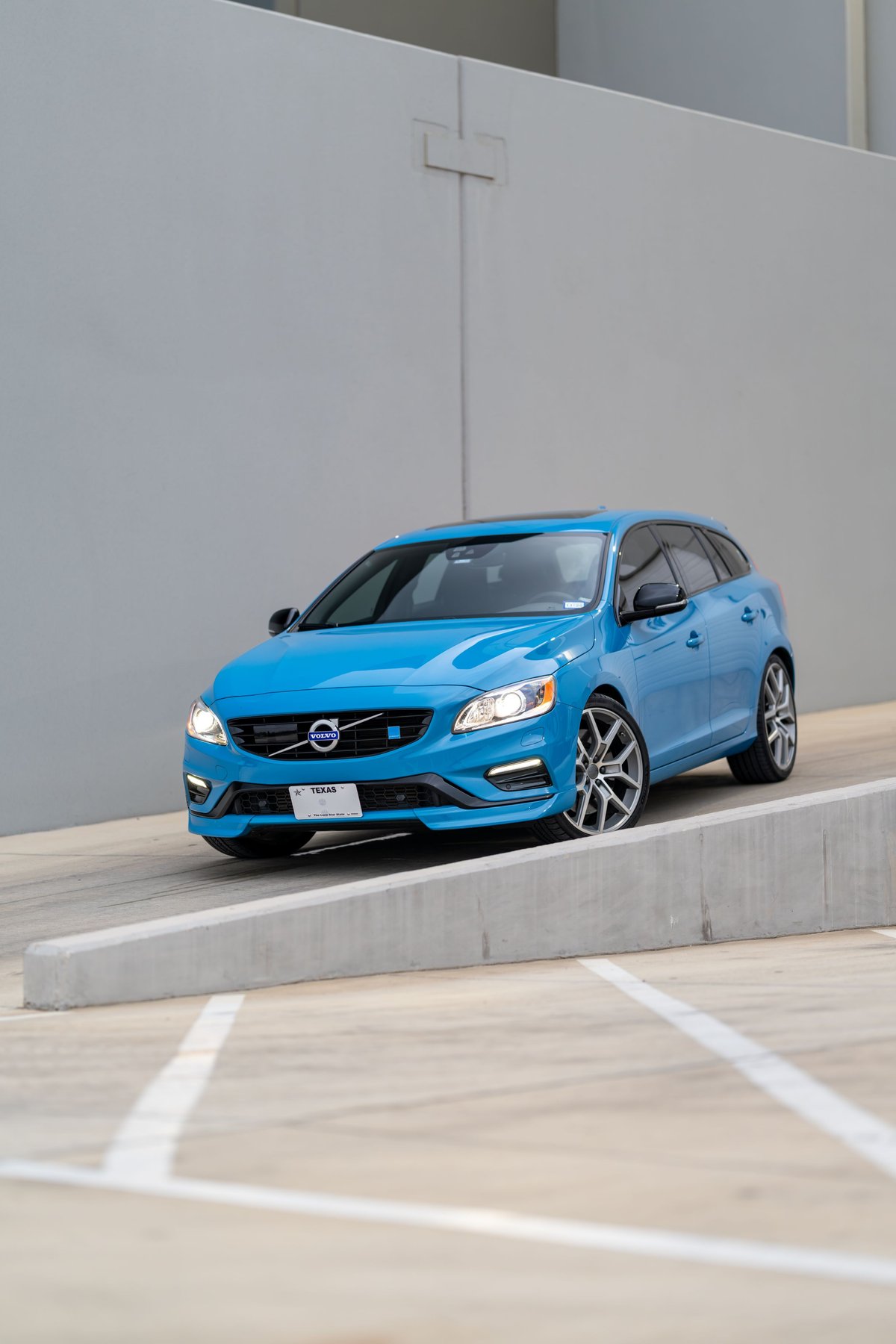 A Rebel Blue 2015 Volvo V60 Polestar with silver rims and black trim is parked on a ramp.