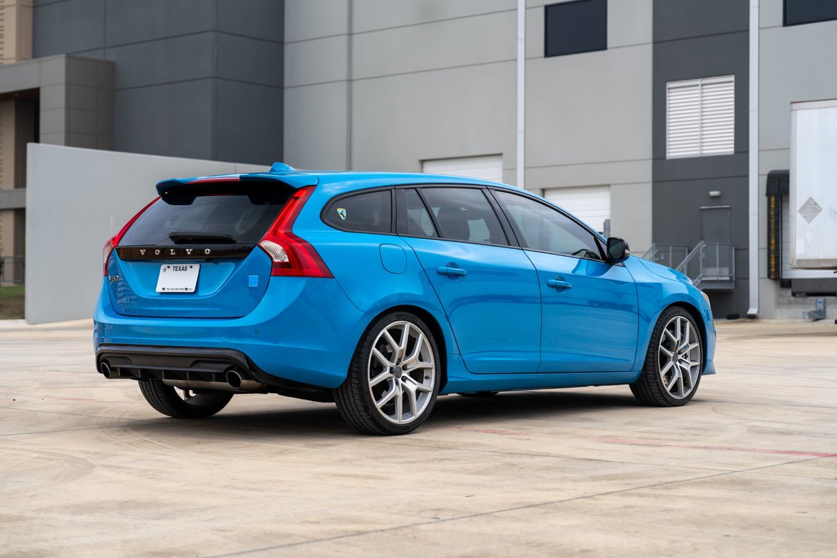 2015 Volvo V60 Polestar wagon in Rebel Blue, showing rear 3/4 view with silver alloy rims and black trim.