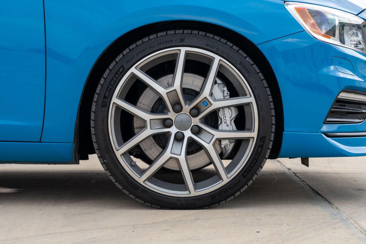Blue 2015 Volvo V60 Polestar wheel with silver multi-spoke rims and Brembo brakes.