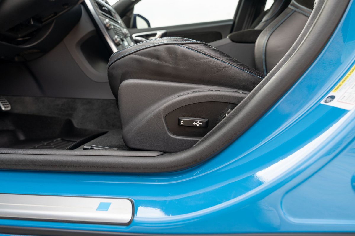 Close-up of a blue 2015 Volvo V60 Polestar's driver's seat control and interior door trim.