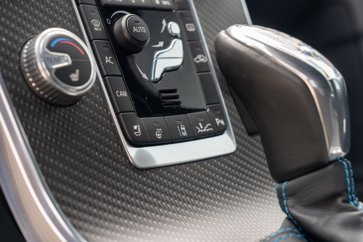 2015 Volvo V60 Polestar Rebel Blue interior featuring carbon fiber trim, climate controls, and gear shifter.
