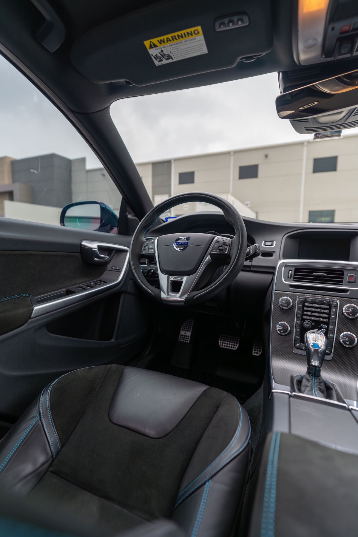 Interior view of a Rebel Blue 2015 Volvo V60 Polestar, featuring sporty seats and carbon fiber trim.