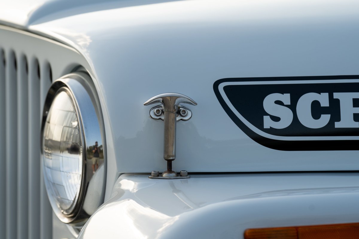 White 1983 Jeep Scrambler with a chrome hood latch and Scrambler badge.