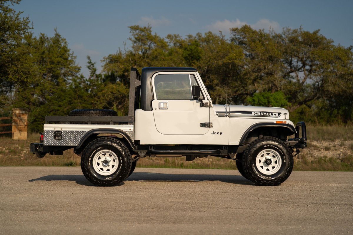 1983 Jeep Scrambler pickup in white with a flatbed and off-road tires.