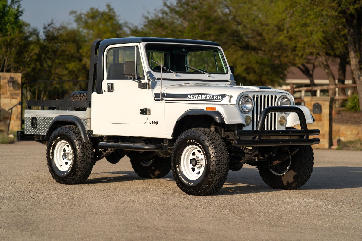 White 1983 Jeep CJ-8 Scrambler with flatbed, black trim, white rims, and "SCRAMBLER" livery.