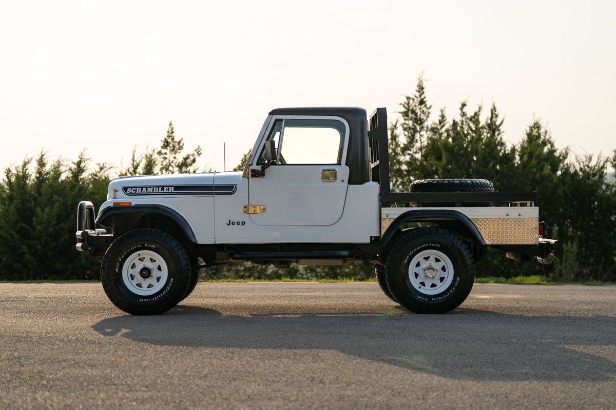 White 1983 Jeep CJ-8 Scrambler with flatbed, white rims, and black trim.