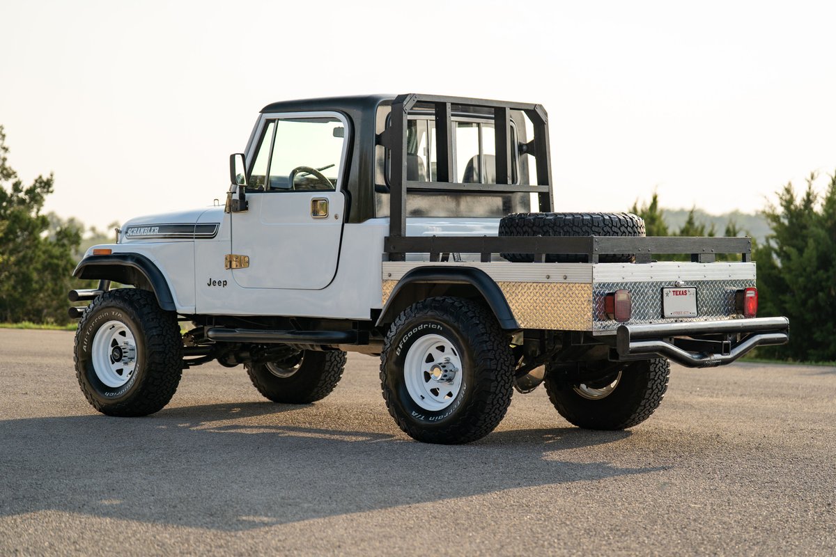 White 1983 Jeep CJ-8 Scrambler with a flatbed, black hardtop, and white rims.