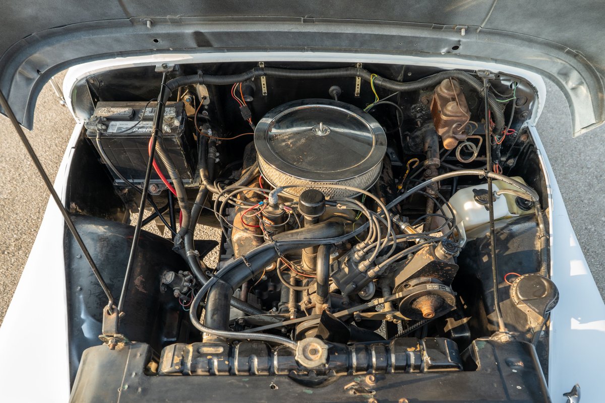 1983 Jeep Scrambler engine bay, white. Vintage inline-4 engine with chrome air cleaner.