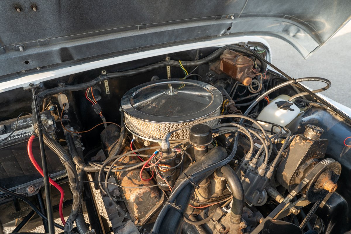 1983 Jeep Scrambler engine bay with chrome air cleaner, distributor, and brake fluid reservoir.