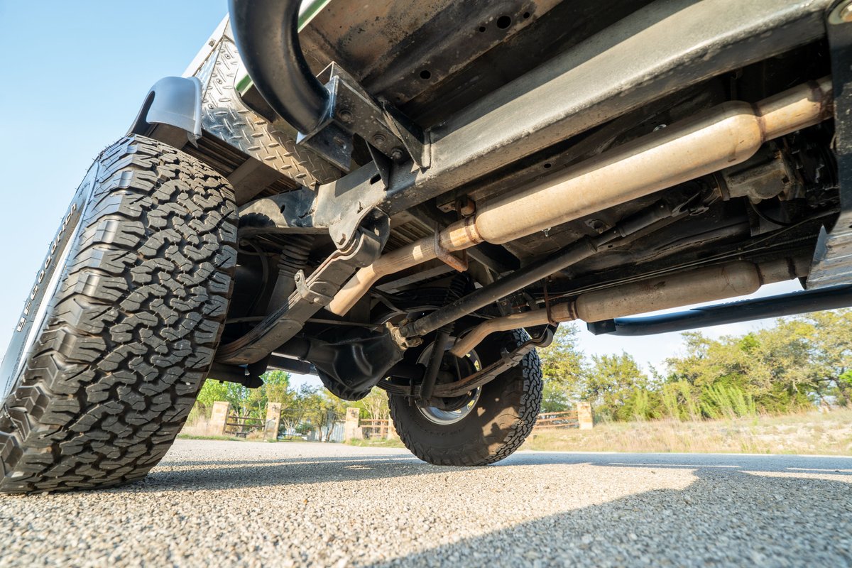 1983 white Jeep Scrambler rear leaf spring suspension and exhaust system.