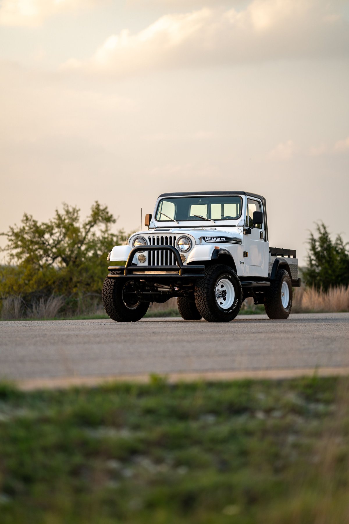 White 1983 Jeep CJ8 Scrambler with black trim, white rims, and off-road tires.