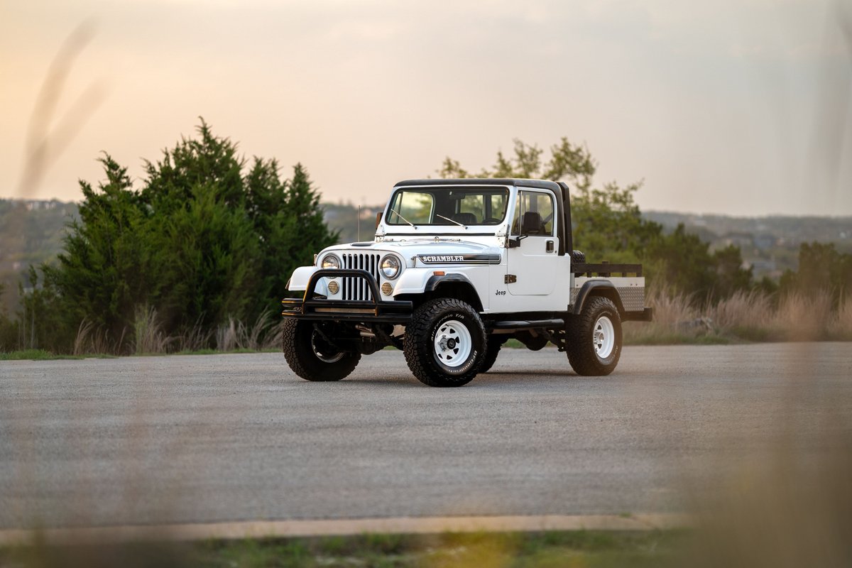 White 1983 Jeep CJ-8 Scrambler pickup truck with white rims and black trim.