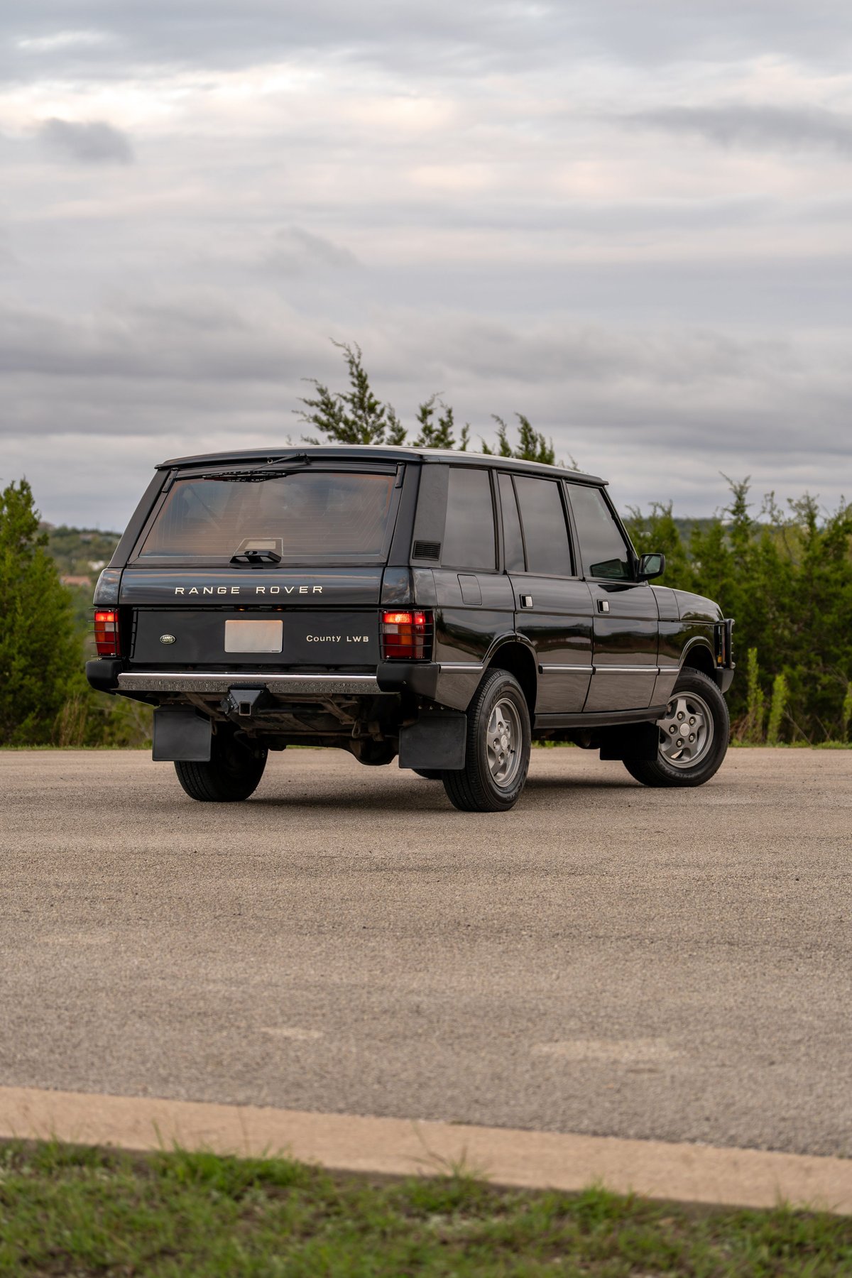 1994 black Range Rover County LWB rear 3/4 view with chrome trim and factory rims.