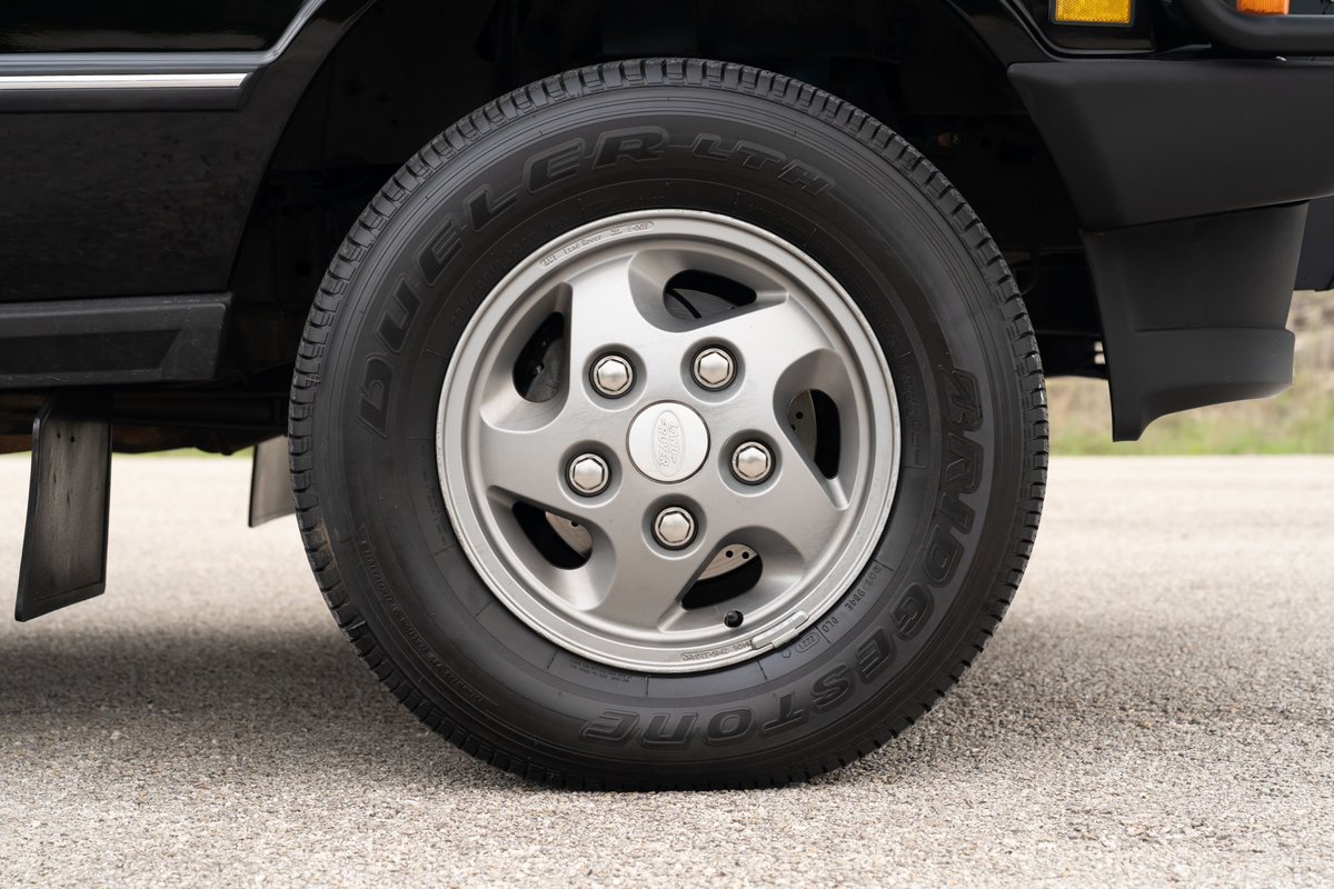 Close-up of a 1994 Range Rover County LWB's silver 5-spoke alloy rim and tire.