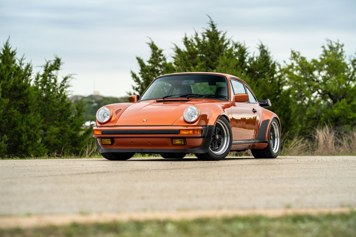 Front view of an orange metallic 1986 Porsche 930 Turbo with black trim and classic rims.