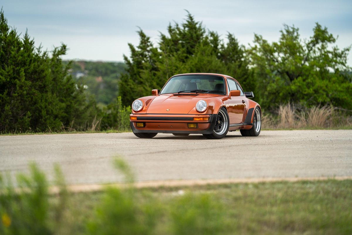 Front view of an orange metallic 1986 Porsche 930 Turbo with black Rims.