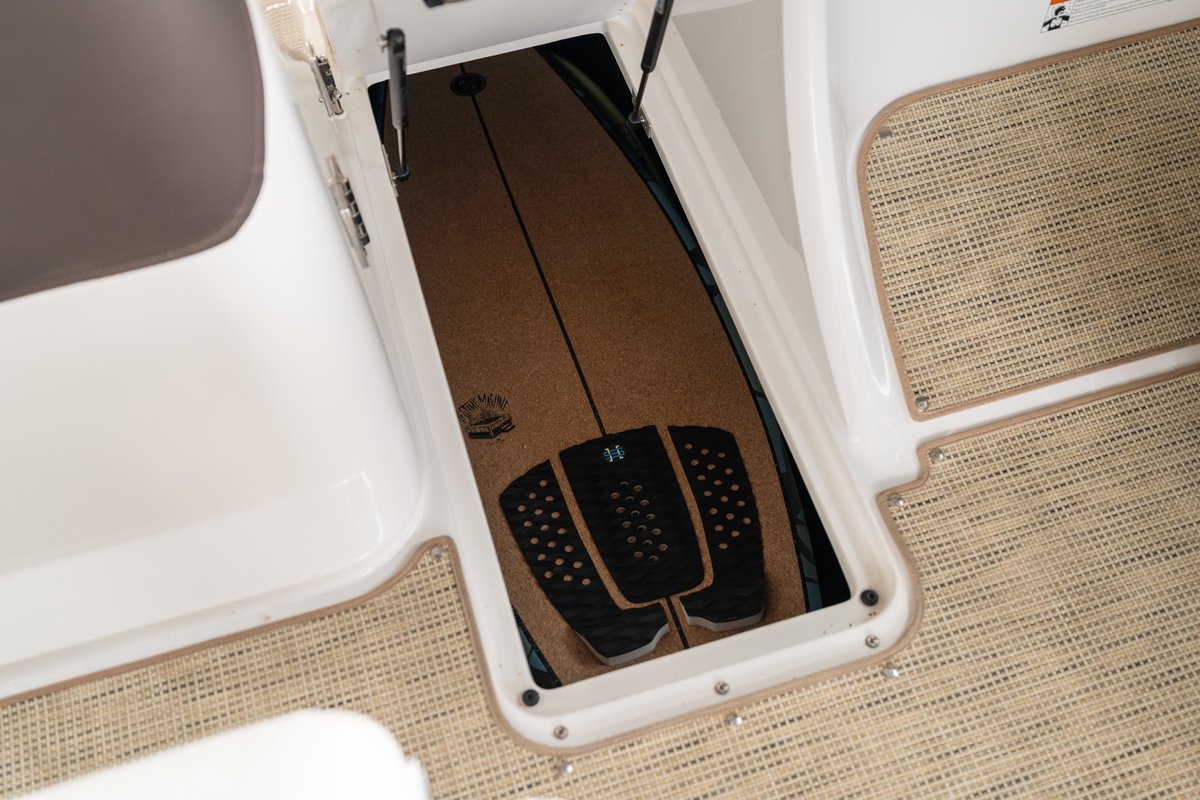 Cobalt R7 Surf boat with a wakeboard stored in a bow locker, featuring a cork deck.