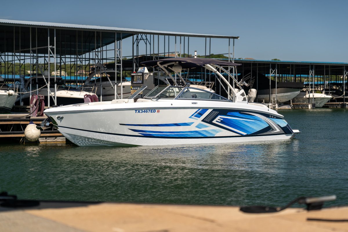 White 2018 Cobalt R7 Surf boat with blue graphic livery in a marina.