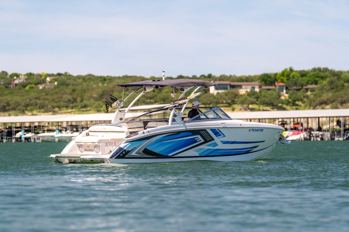Cobalt R7 Surf boat with blue wave livery on a lake.