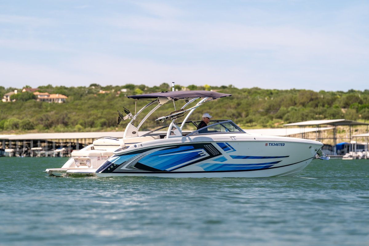 2018 Cobalt R7 Surf boat with blue wave livery, white hull and wakeboard tower.