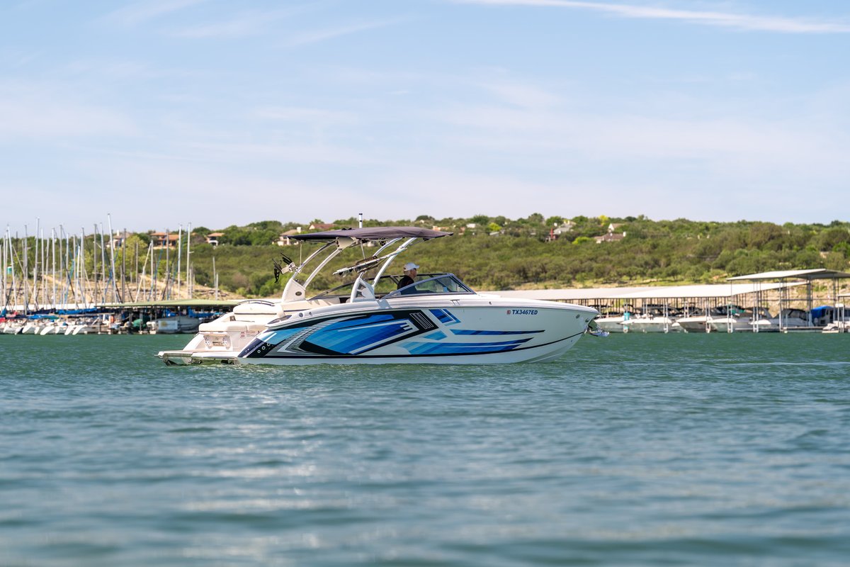 2025 Cobalt R7 Surf boat with a striking blue and white livery design on a calm lake.
