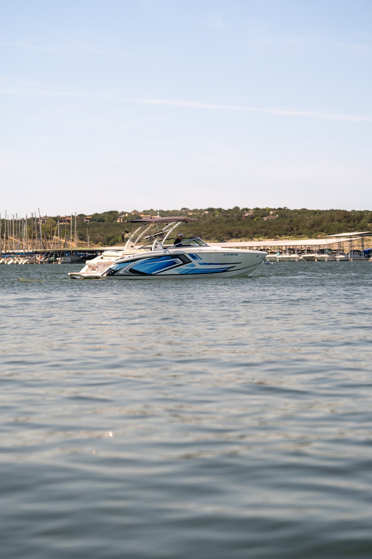 White 2018 Cobalt R7 Surf boat with a blue wave livery speeds through the water.
