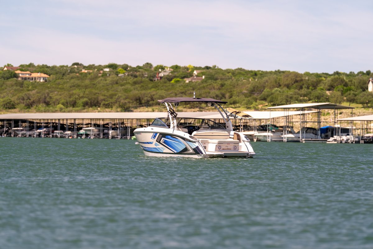 A white 2018 Cobalt R7 Surf boat with blue trim and livery cuts through the water.