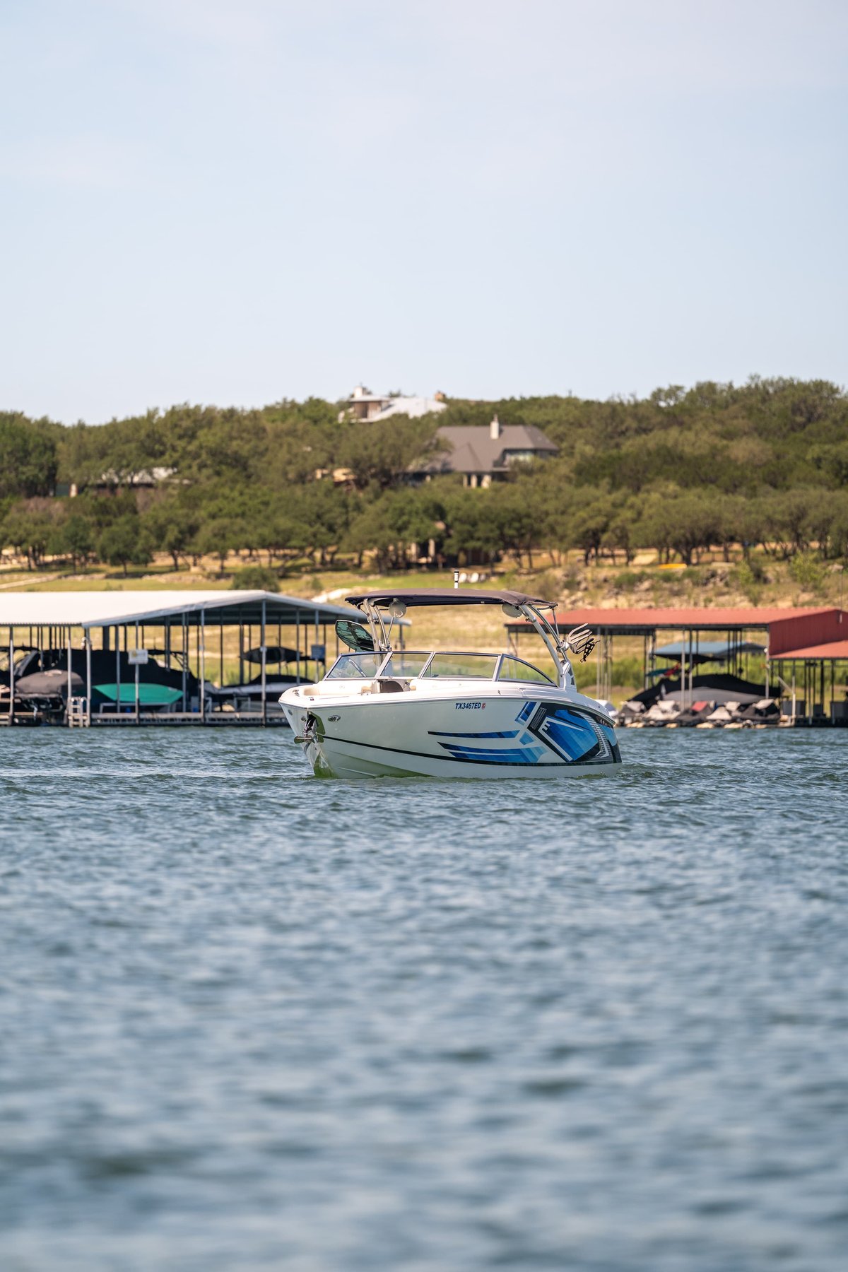 White 2018 Cobalt R7 Surf boat with blue accents, parked at a dock on a sunny day.