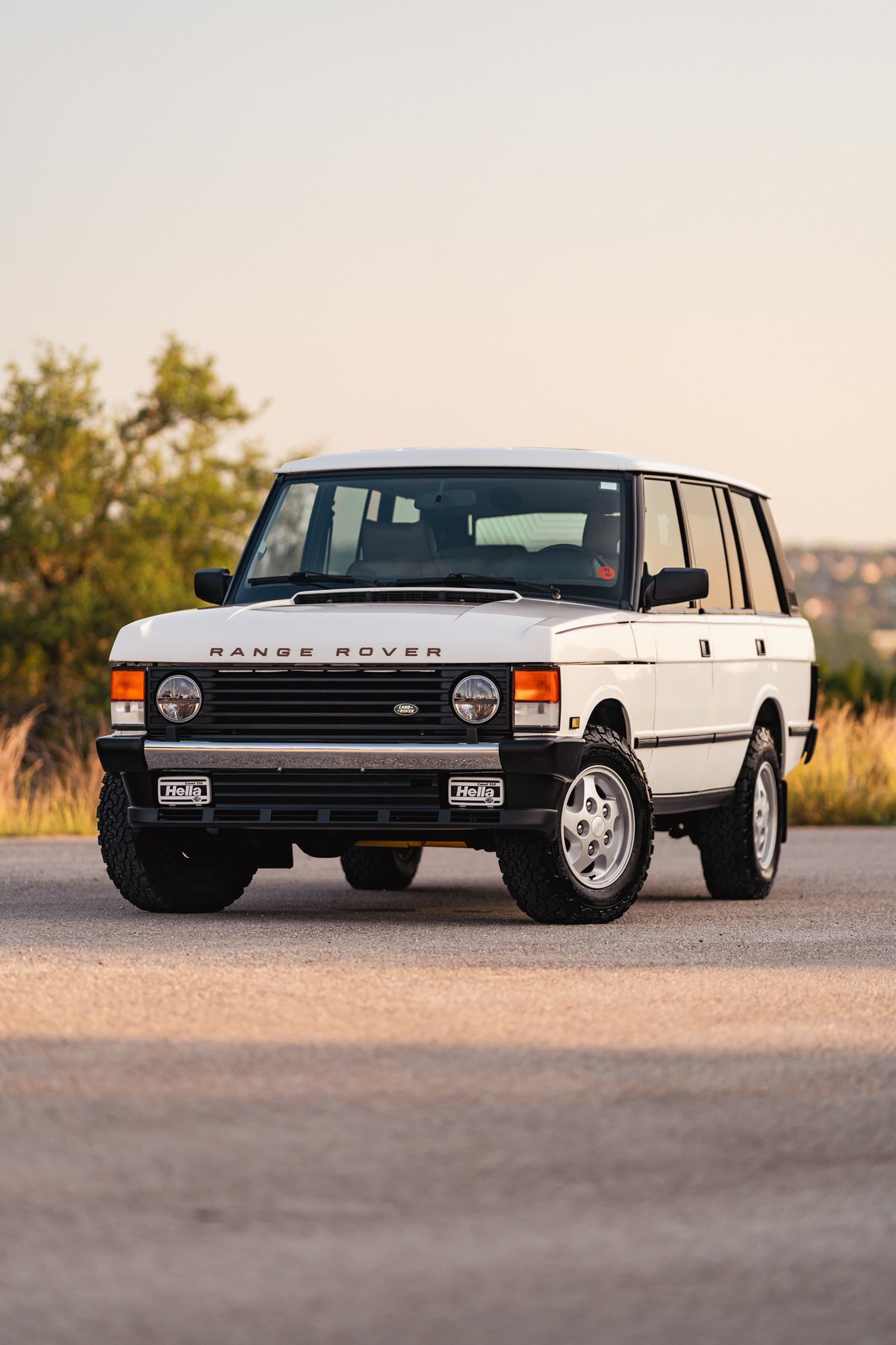 Front view of a white 1995 Range Rover County with Hella lights and silver rims.